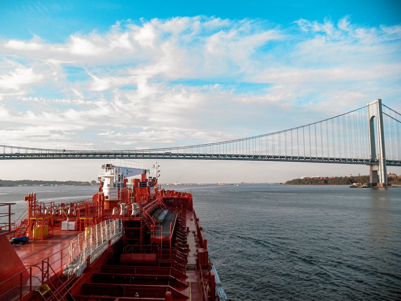 Services Tanker ship navigating under the iconic Verrazzano-Narrows Bridge on a clear day.