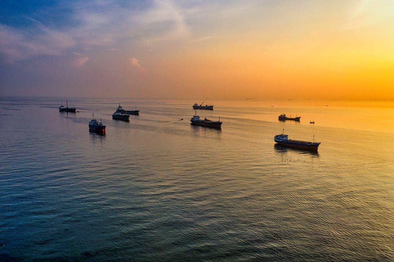 Services A stunning aerial view of ships silhouetted against a golden sunset over Jakarta
